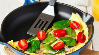 Omelette with green bean. spinach and tomato in a skillet.