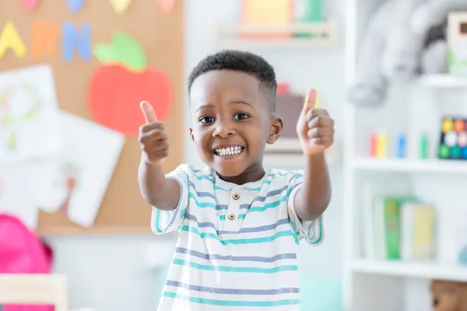 Adorable boy gives thumbs up in preschool