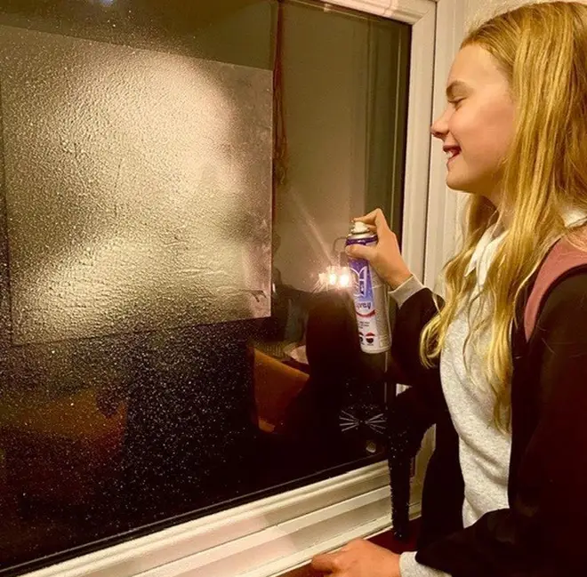 Gently stick the stencil to the window and spray the fake snow