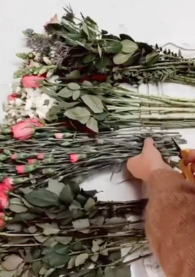 The woman use a collection of flowers from a supermarket