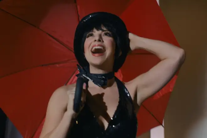 Liza is played by Krysta Rodriguez in Halston