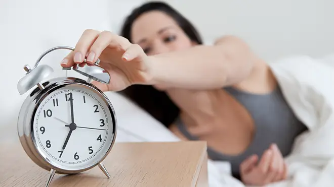 Woman turning off her alarm clock