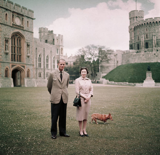 The Queen walks with her husband and Corgi in the grounds of the Windsor Estate