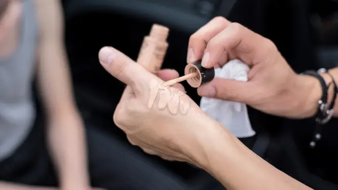 Woman applies make-up to the back of her hand