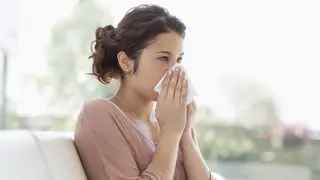 Woman blowing her nose and feeling unwell
