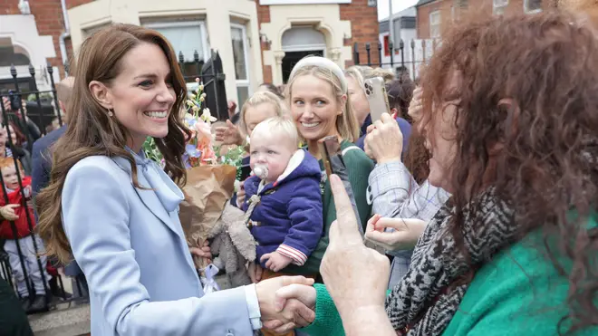 The Duchess of Cambridge and Cornwall smiles nervously as she listens to the woman's heckles