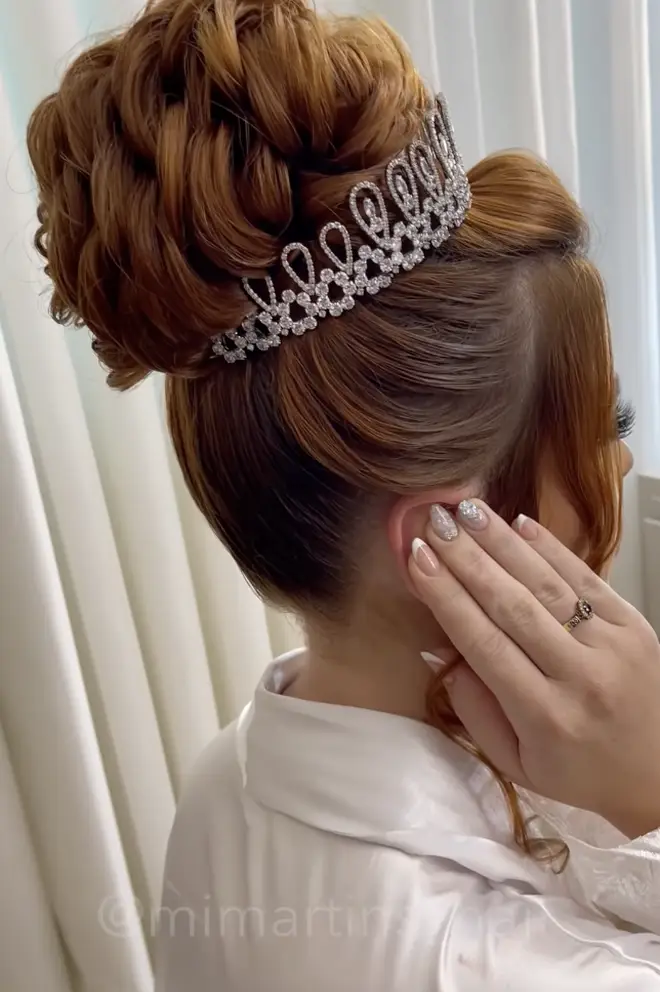 The bride holds her ears back after the beautician applies the glue to the back of her ear