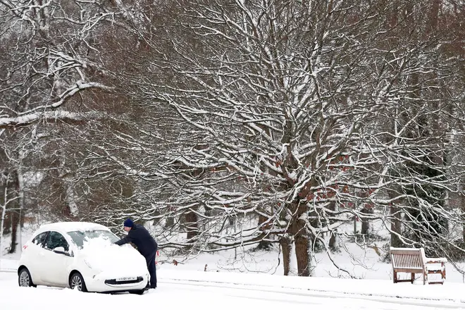 A man sweeping the snow off his car this morning