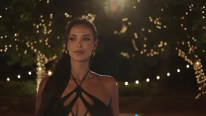 Maya Jama walking into the Love Island villa wearing a sexy black dress and gold earrings
