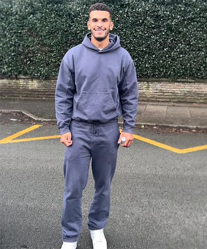 Love Island's Kai Fagan posing awkwardly in the street in a blue tracksuit
