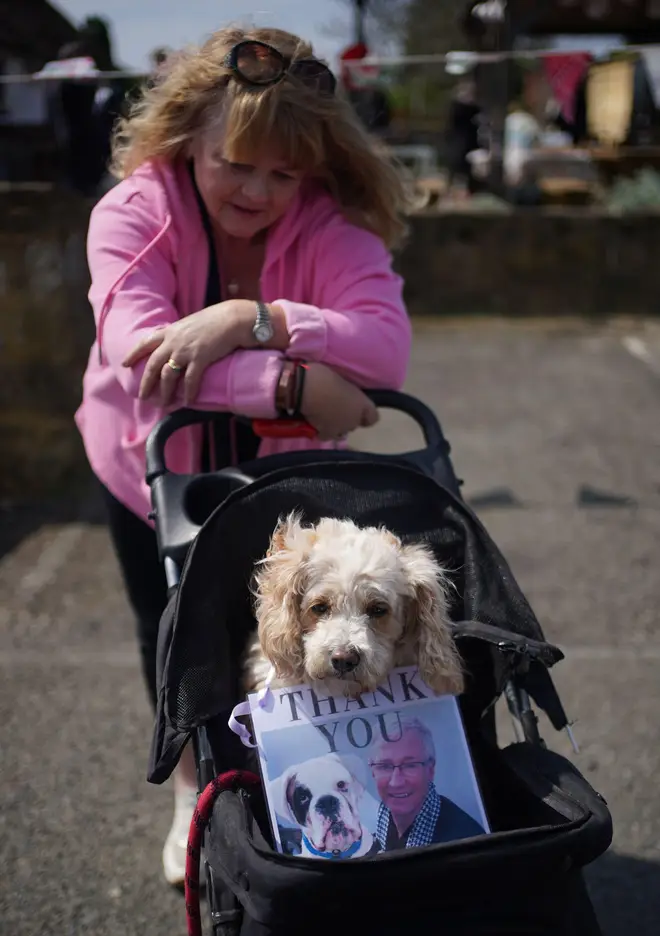 A woman and her dog wait in the streets to say goodbye to Paul O'Grady