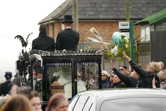 Well-wishers throw flowers onto Paul O'Grady's coffin as it travels through the town in Kent