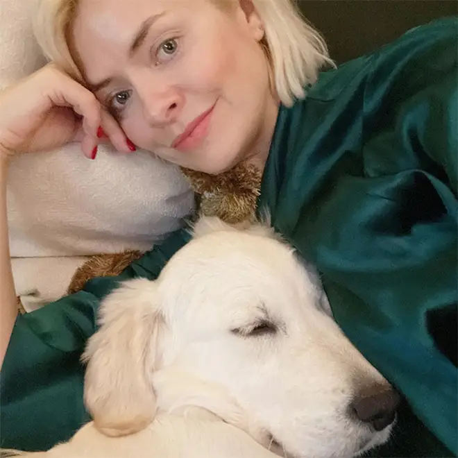 Holly Willoughby laying down and cuddling their family dog Bailey who is a golden retriever