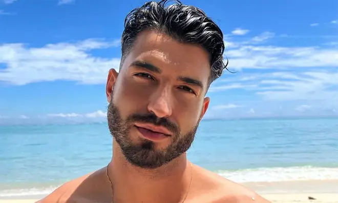 Love Island Mehdi Edno posing with slick back black hair on a beach