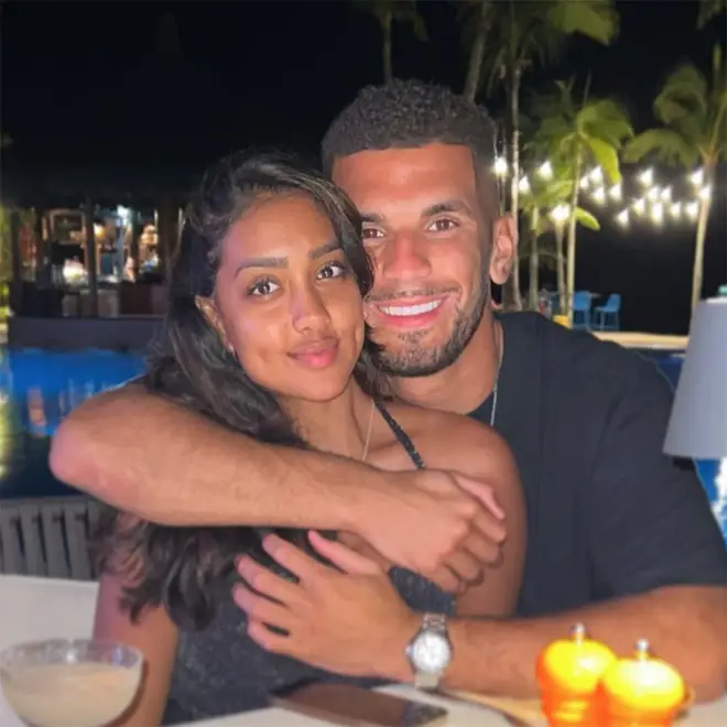 Love Island winners Kai and Sanam cuddling at a restaurant on holiday