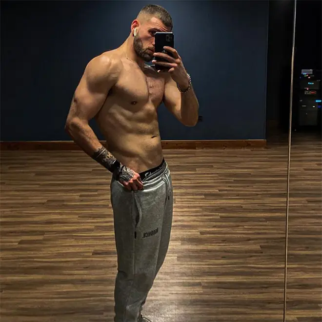 Zachariah Noble taking a gym mirror selfie in grey joggers showing of his muscle definition and six pack