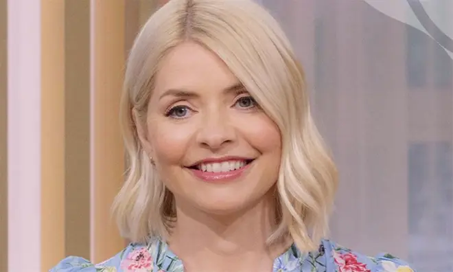 Holly Willoughby smiling into the camera wearing a blue and pink floral dress