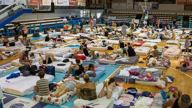 Holidaymakers and residents sleeping in beds in a school hall after being evacuated