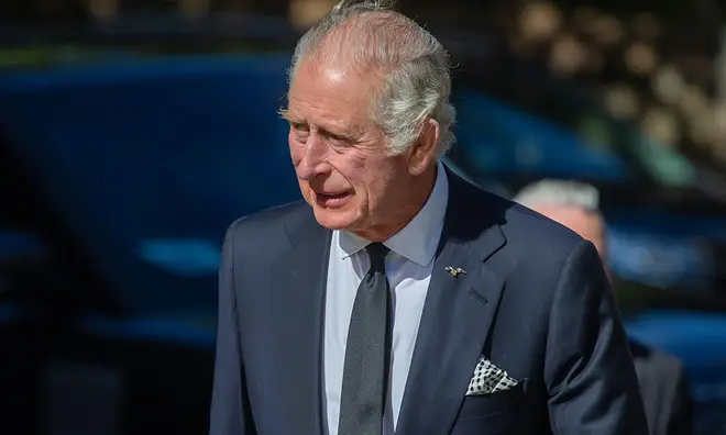 King Charles on a street appointment wearing a navy suit and tie