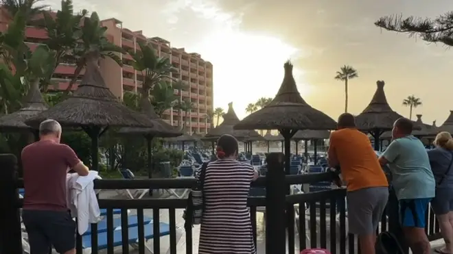 People queue outside the pool area at a hotel in Benalmadena as they wait to reserve sun loungers