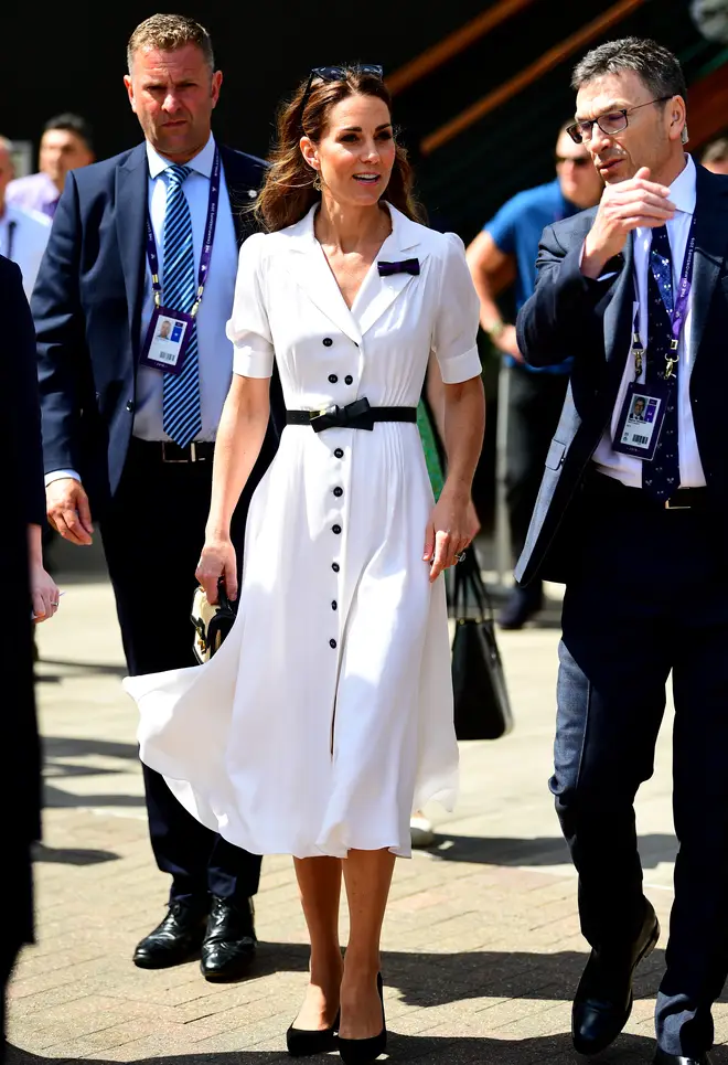 Kate Middleton is wearing a classic white tea dress, with black bow belt and court shoes