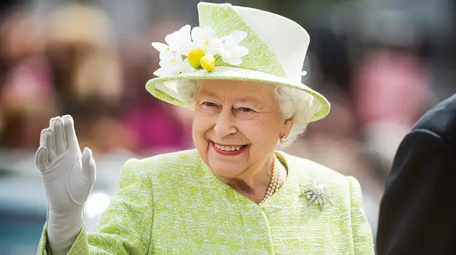 Queen Elizabeth II wearing a lime green outfit while smiling and waving