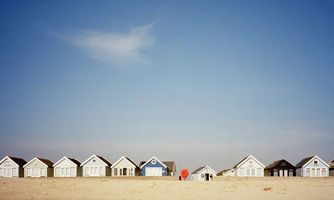Beach huts on a beach against a clear blue sky