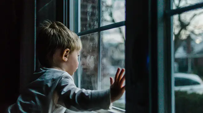 Young boy looking out of a window