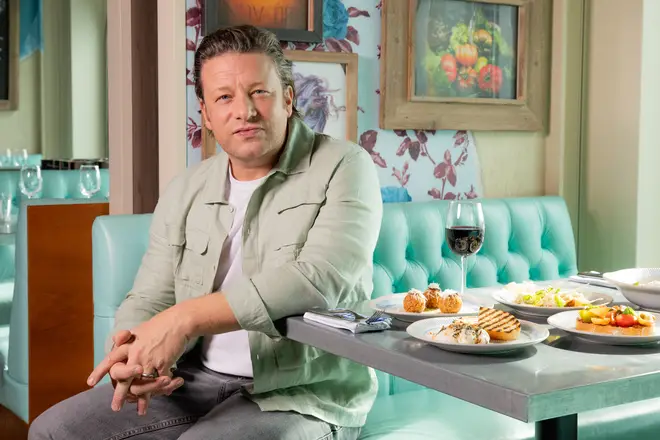 Jamie Oliver smiles at dinner table