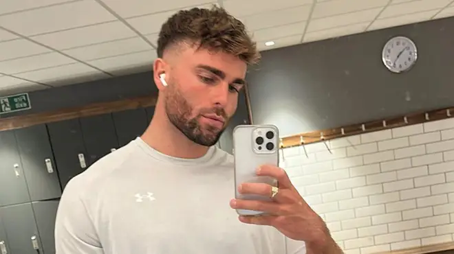 Tom Clare in a white t-shirt taking a gym selfie