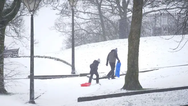 People carry sledges up snowy hill