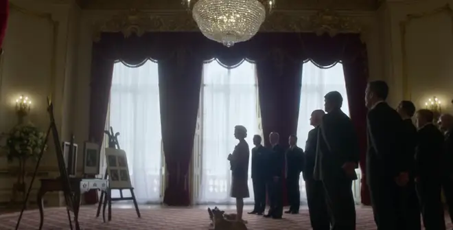 The trailer shows the Queen enter a large room full of staff