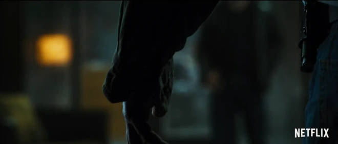 A mystery man with a gun is seen in the trailer